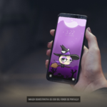 Mano de una mujer sosteniendo su móvil con el fondo de pantalla de Wachi brujita en movimiento.