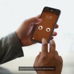 Mano sosteniendo un móvil con el fondo de pantalla de Wachi, el perro chihuahua, en un elegante fondo blanco.