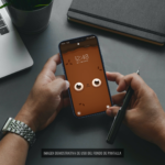 Par de manos sosteniendo un teléfono celular con el fondo de pantalla de Wachi.